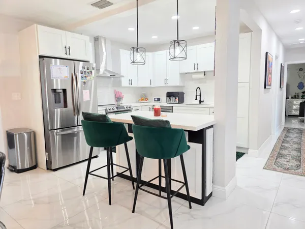 a kitchen with stainless steel appliances kitchen island a refrigerator and a stove top oven