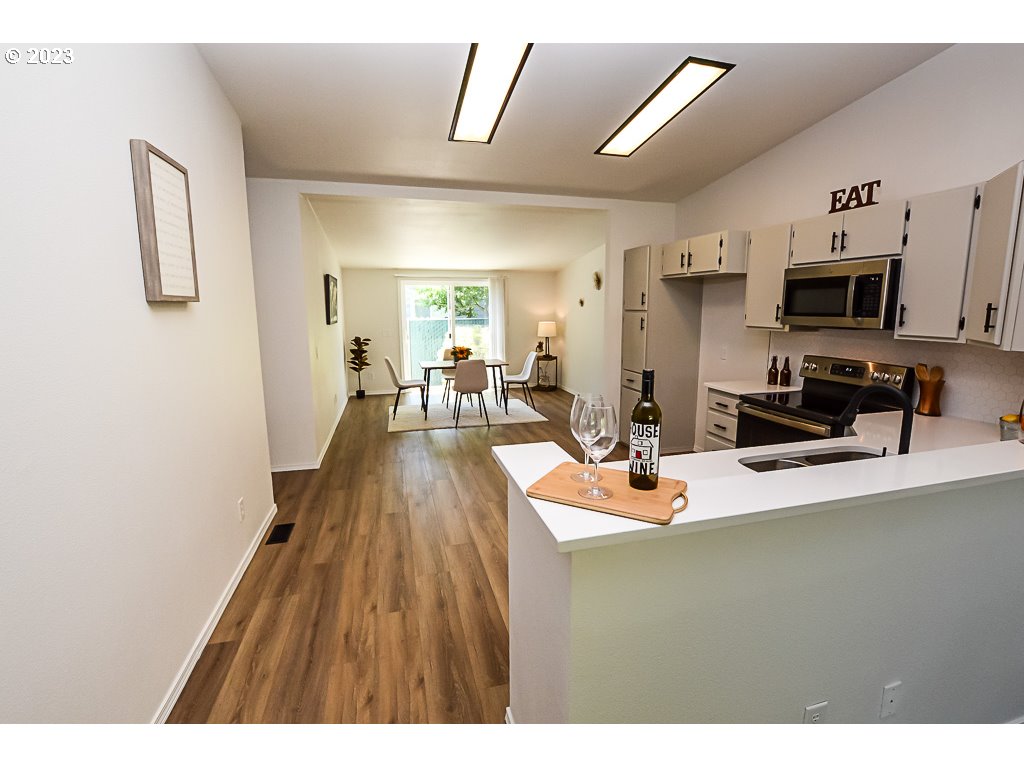 5332 Bridgewater Drive Eugene, OR 97402 - Photo 10 of 28 a dining room with stainless steel appliances kitchen island granite countertop a refrigerator a stove a oven with white cabinets and wooden floor