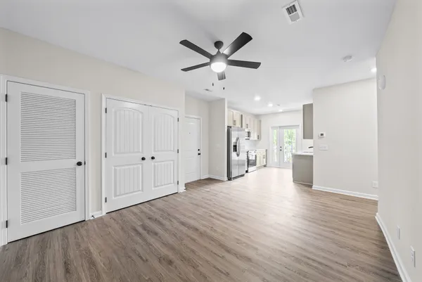 a view of an empty room with wooden floor and a ceiling fan