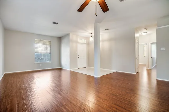 a view of an empty room with window and wooden floor