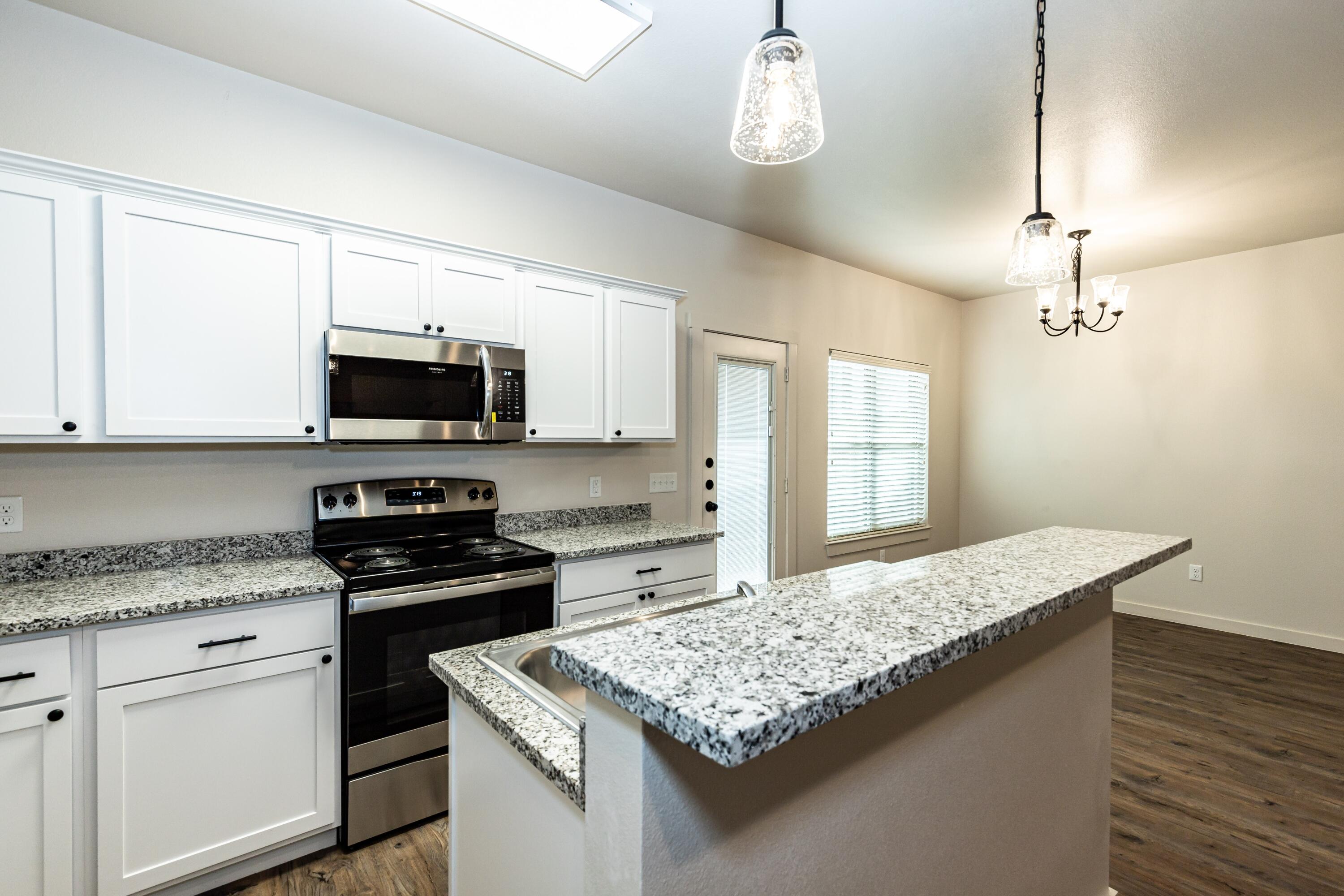 2529 138th Street Lubbock, TX 79423 - Photo 9 of 24 a kitchen with granite countertop stainless steel appliances a stove microwave and sink