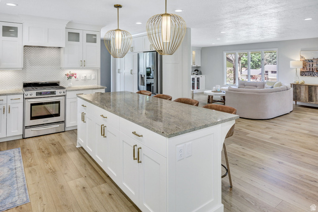 1350 Canyon Park Road Bountiful, UT 84010 - Photo 11 of 38 Kitchen featuring a large center island with a stone countertop, white shaker cabinetry with brass hardware, and wood-finish flooring