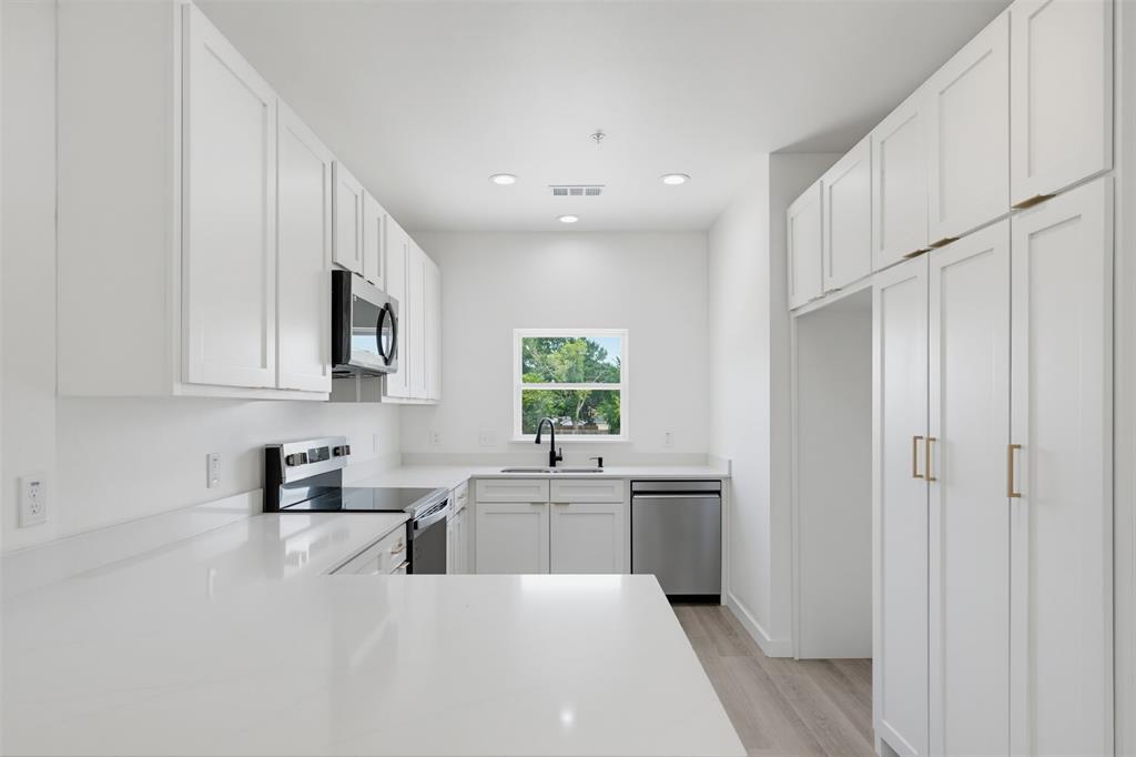 512 South O Connor Road Irving, TX 75060 - Photo 2 of 21 Modern kitchen featuring white shaker cabinetry, light countertops, stainless steel appliances, and wood-finish flooring