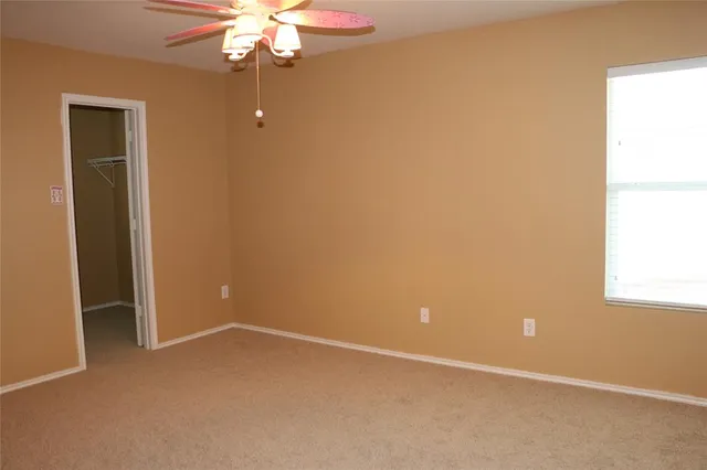 an empty room with a window and a fan
