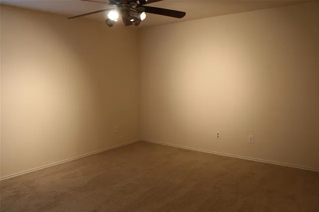 an empty room with a chandelier fan and closet area