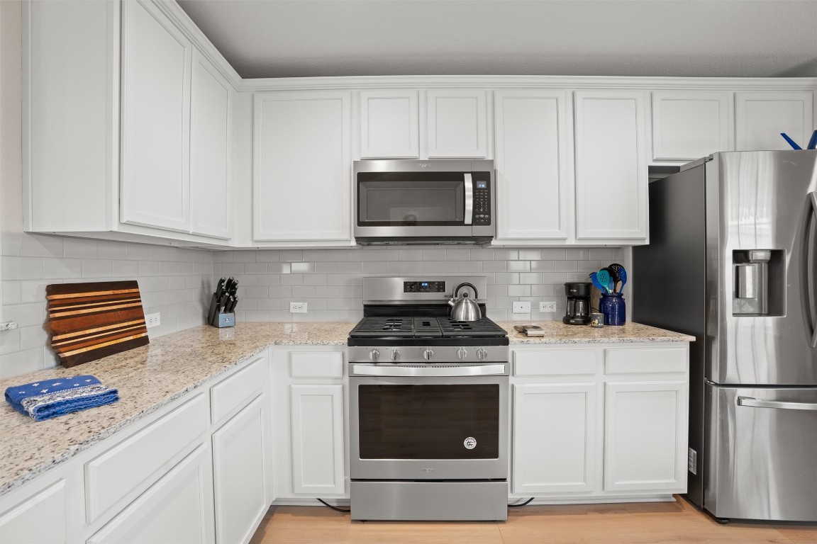 512 Rockport Street Georgetown, TX 78633 - Photo 7 of 26 a kitchen with granite countertop white cabinets and stainless steel appliances