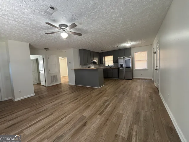 a view of a big room with wooden floor and windows