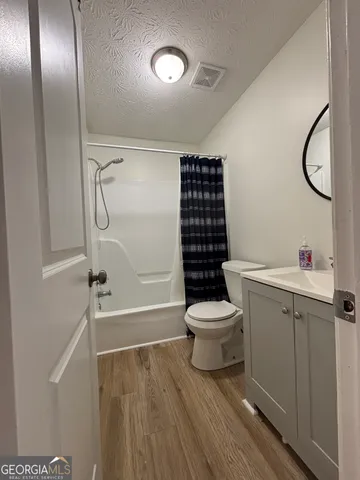 a bathroom with a granite countertop sink toilet a mirror and shower