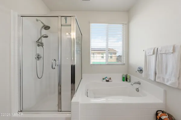 a bathroom with a bathtub a shower and a window