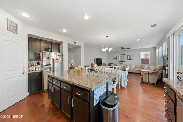 a room with stainless steel appliances kitchen island granite countertop a table chairs and a refrigerator
