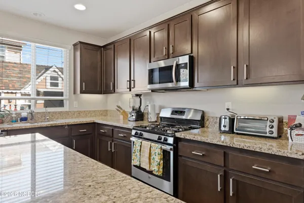 a kitchen with stainless steel appliances granite countertop a stove a sink dishwasher and a microwave oven with cabinets