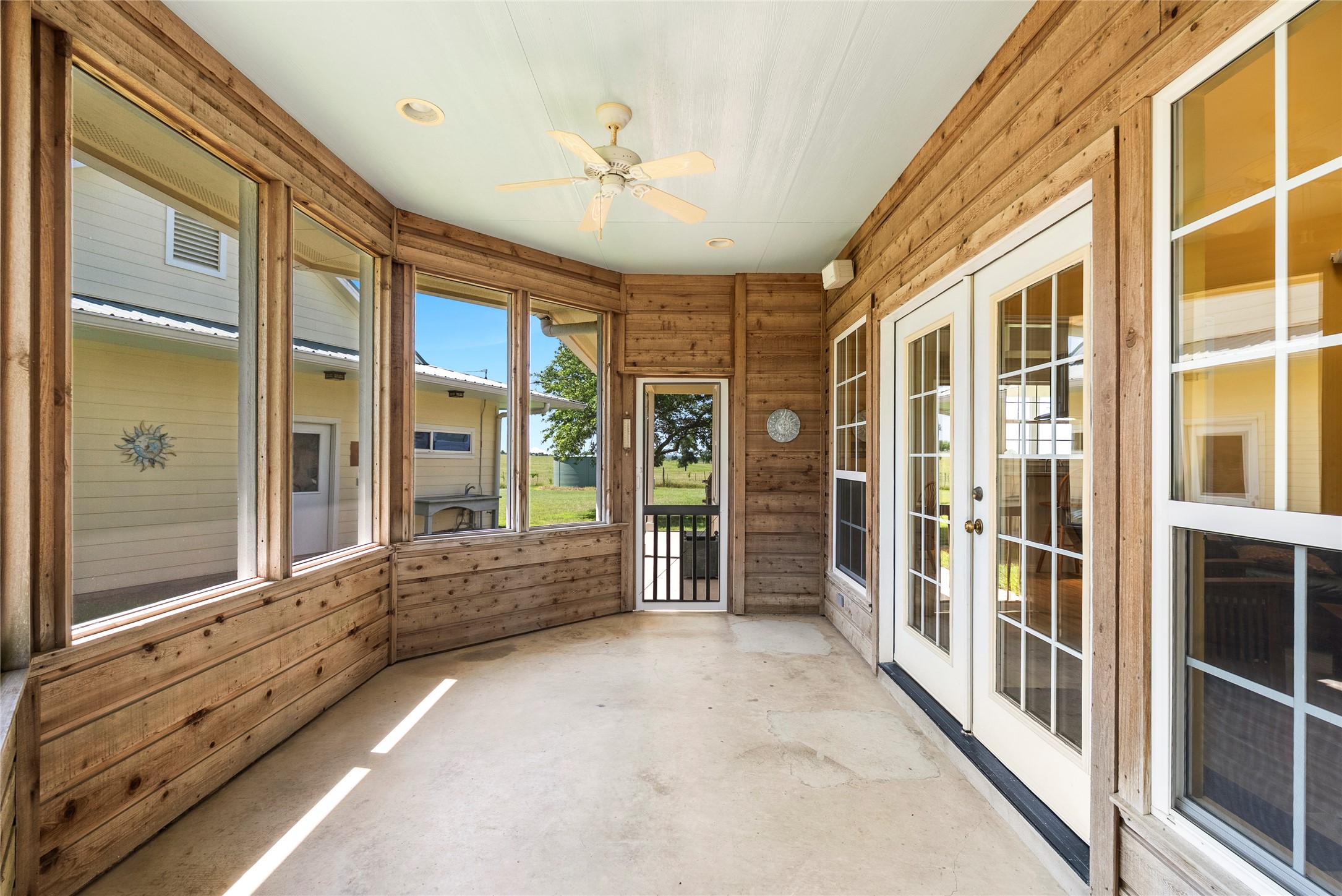 928 Upper Elgin River Road Elgin, TX 78621 - Photo 12 of 40 Enclosed porch featuring wood paneling, multiple picture windows, a ceiling fan with integrated lighting, and recessed lighting.