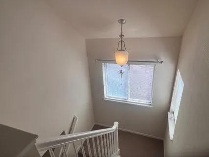 a view of hallway with window and wooden floor