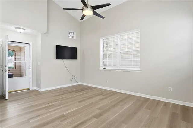 an empty room with wooden floor fan and windows