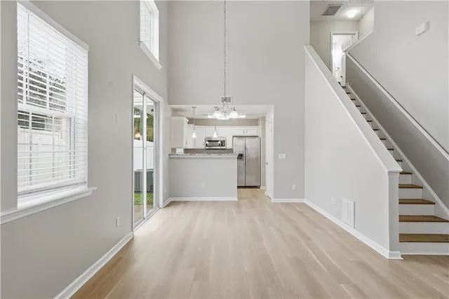 a view of a kitchen with wooden floor electronic appliances and stairs
