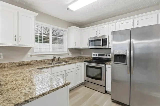 a kitchen with granite countertop a sink stove and refrigerator
