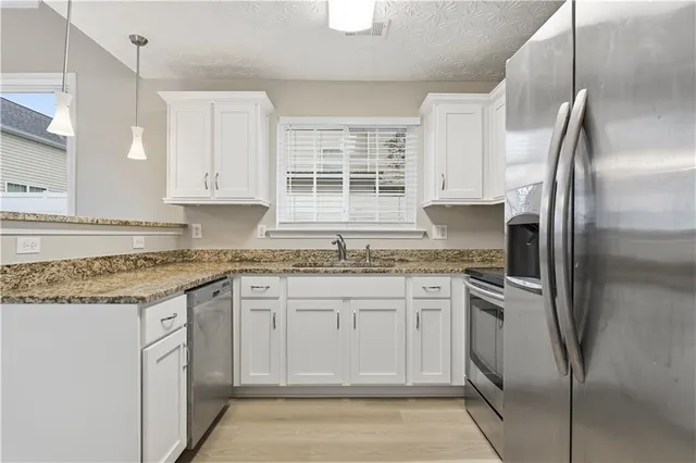 a kitchen with stainless steel appliances granite countertop a refrigerator sink and stove