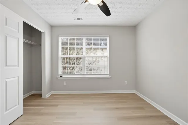 a view of an empty room with chandelier fan and fire place