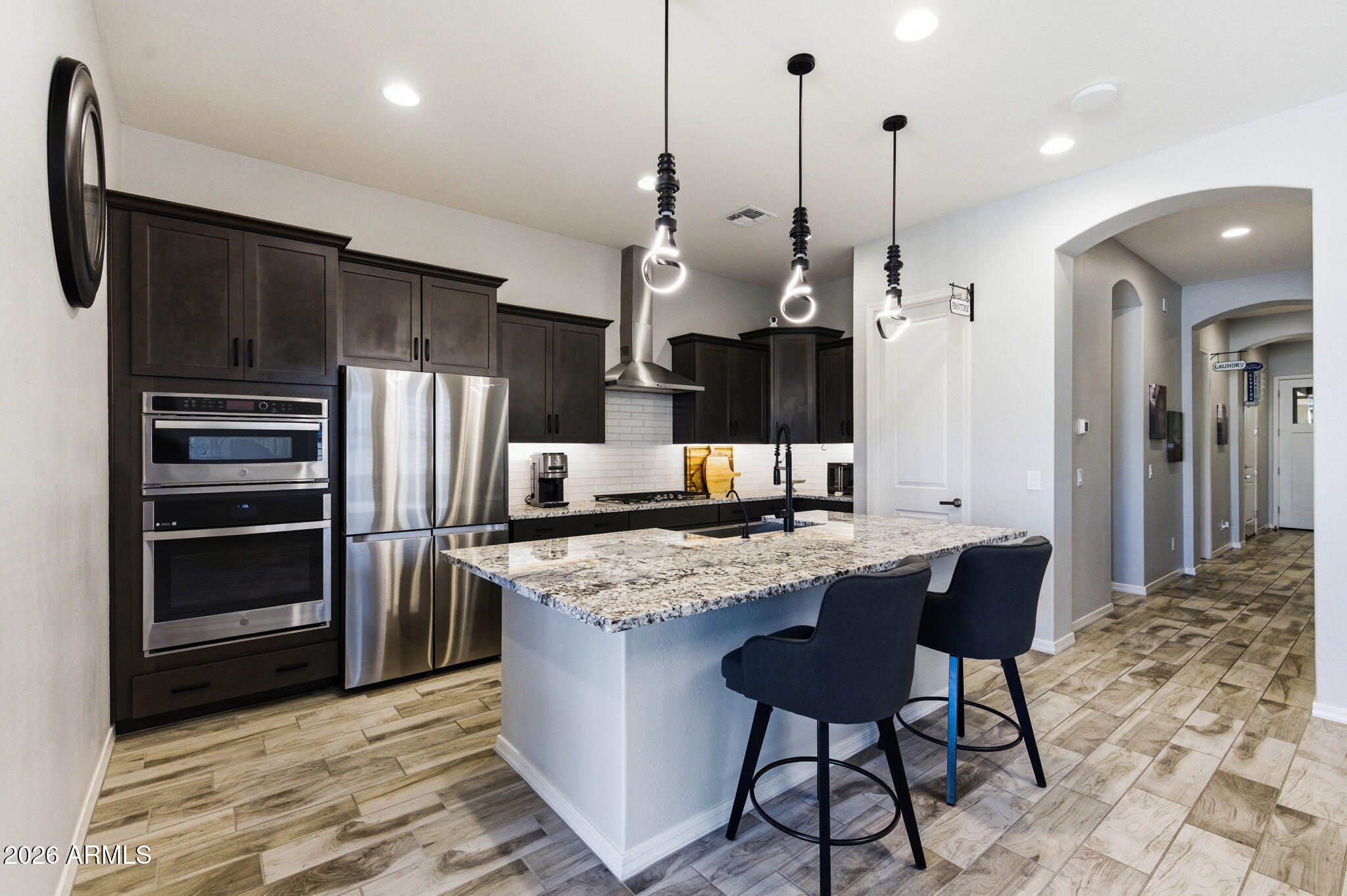 23066 East Mayberry Road Queen Creek, AZ 85142 - Photo 5 of 39 a kitchen with stainless steel appliances granite countertop a sink a stove a refrigerator and island with wooden floor