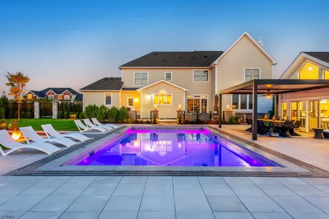 a view of swimming pool with red chairs in front of house