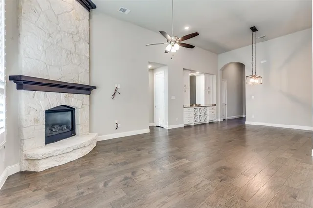 a view of an empty room with chandelier fan and fire place
