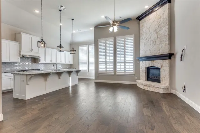 a view of kitchen with granite countertop wooden floor stainless steel appliances and a fireplace
