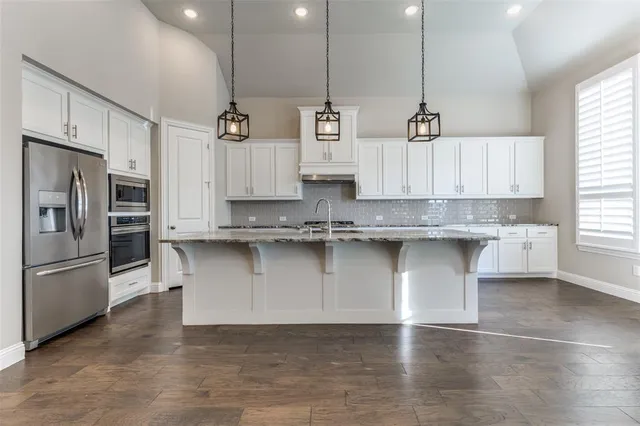 a kitchen with stainless steel appliances granite countertop a sink a stove and a refrigerator