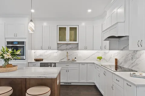 a kitchen with sink stove and white cabinets with wooden floor