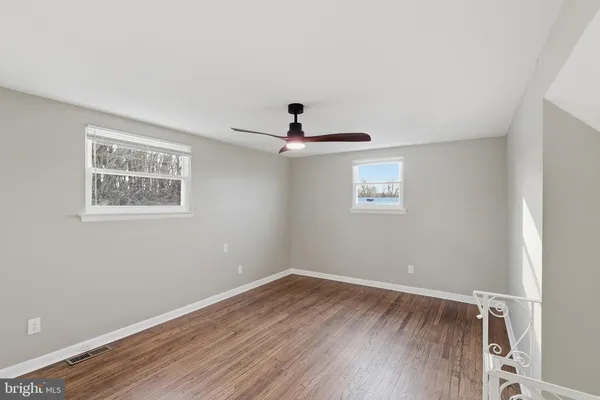 a view of empty room with wooden floor and fan