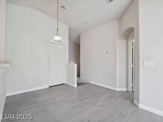 4675 Color Up Court, Unit 101 Las Vegas, NV 89122 - Photo 11 of 19 Unfurnished dining area featuring light wood-type flooring, lofted ceiling, and arched walkways
