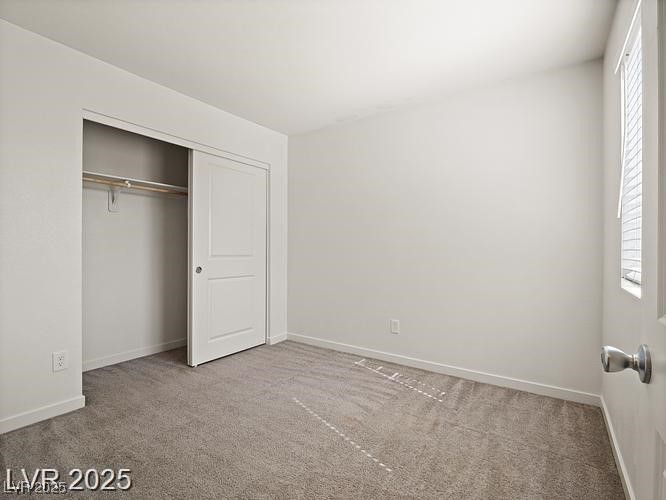 4675 Color Up Court, Unit 101 Las Vegas, NV 89122 - Photo 14 of 19 Unfurnished bedroom featuring light colored carpet, multiple windows, and a closet