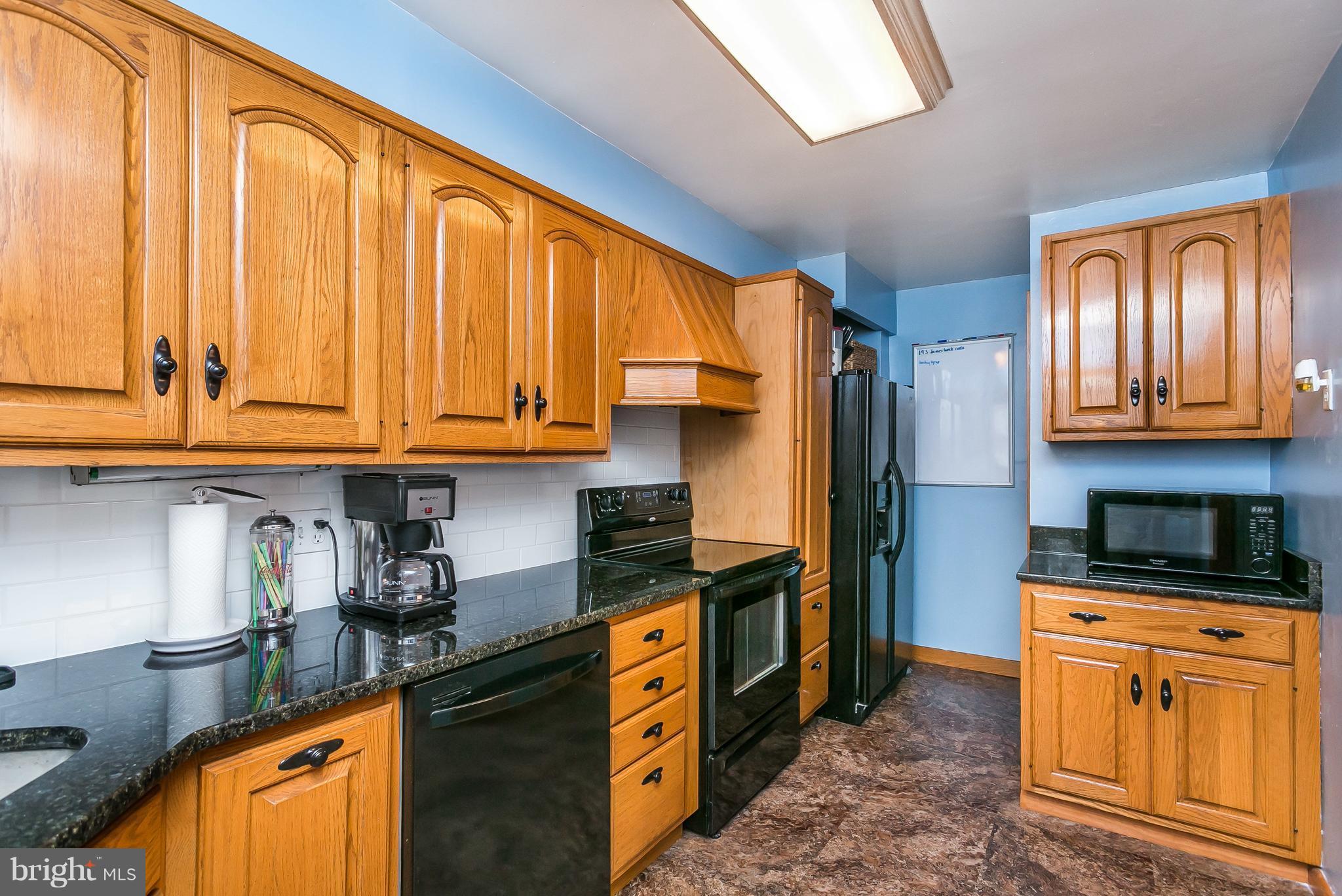 8511 Kings Ridge Road Baltimore, MD 21234 - Photo 10 of 30 a kitchen with stainless steel appliances granite countertop a stove a sink dishwasher and refrigerator with wooden cabinets