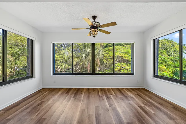 a view of empty room with window ceiling fan and hardwood floor