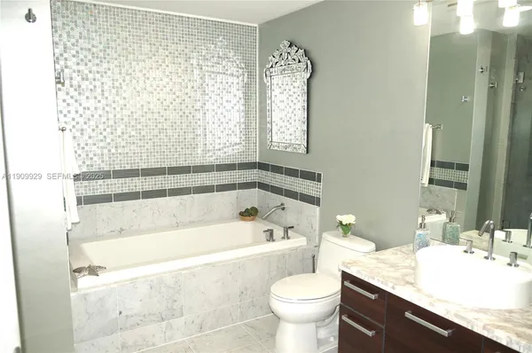 a bathroom with a granite countertop bathtub sink vanity mirror and toilet
