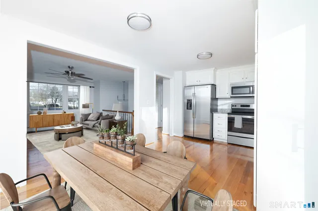 a living room with stainless steel appliances furniture a rug and a kitchen view