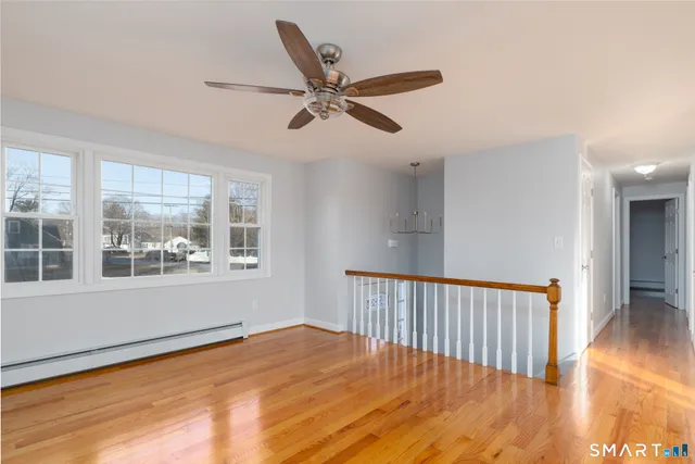 a view of empty room with wooden floor and fan