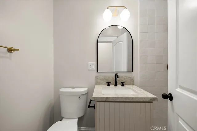 a bathroom with a granite countertop toilet a sink and a mirror