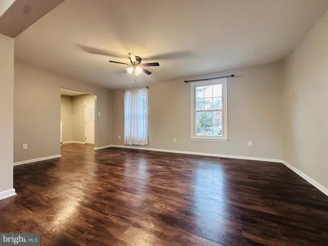 a view of an empty room with window and wooden floor