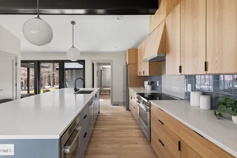 a large white kitchen with a sink and dishwasher a stove with wooden floor