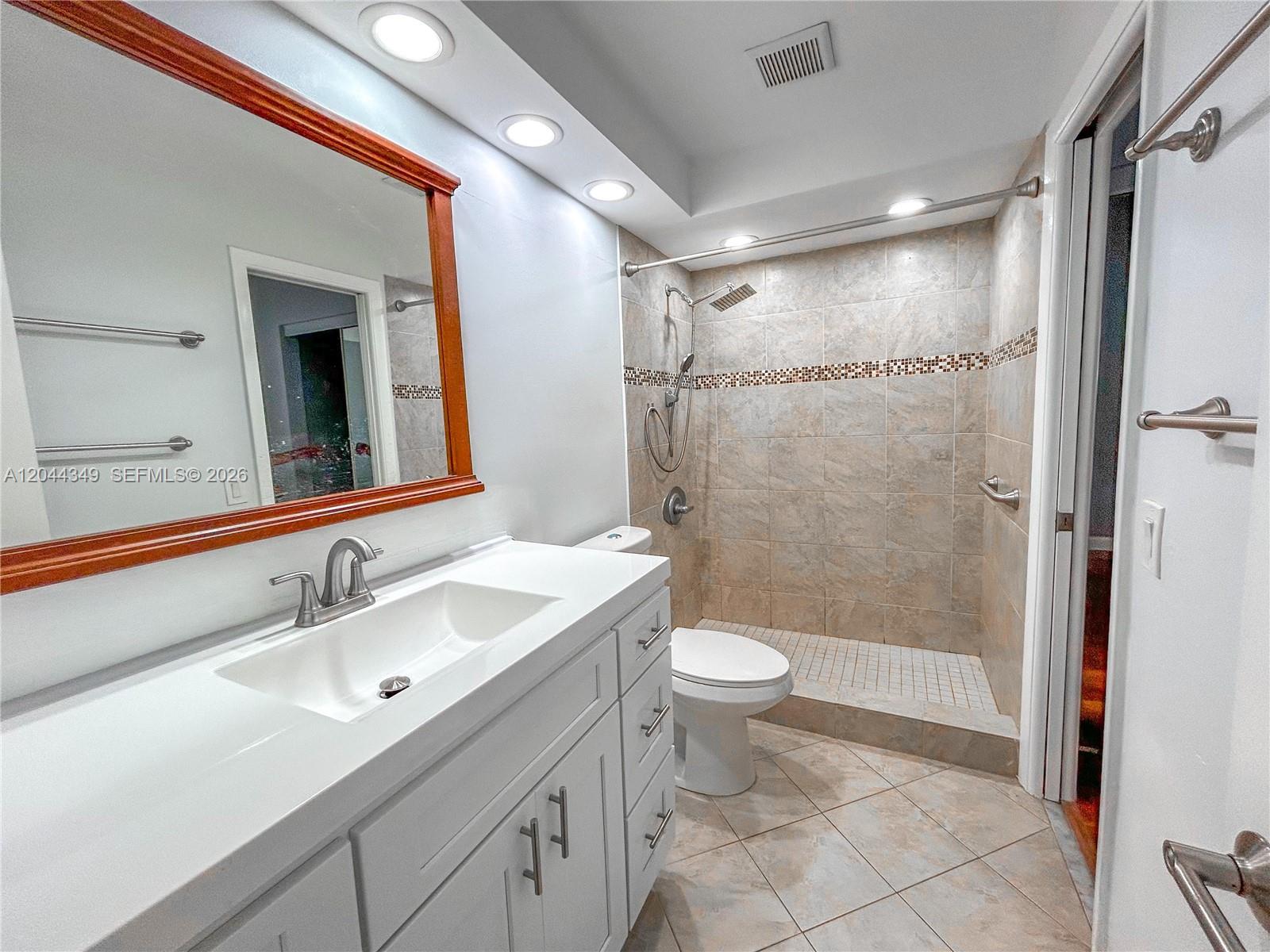 14970 Southwest 48th Terrace, Unit 27G Miami, FL 33185 - Photo 7 of 14 a bathroom with a sink a toilet a mirror and shower