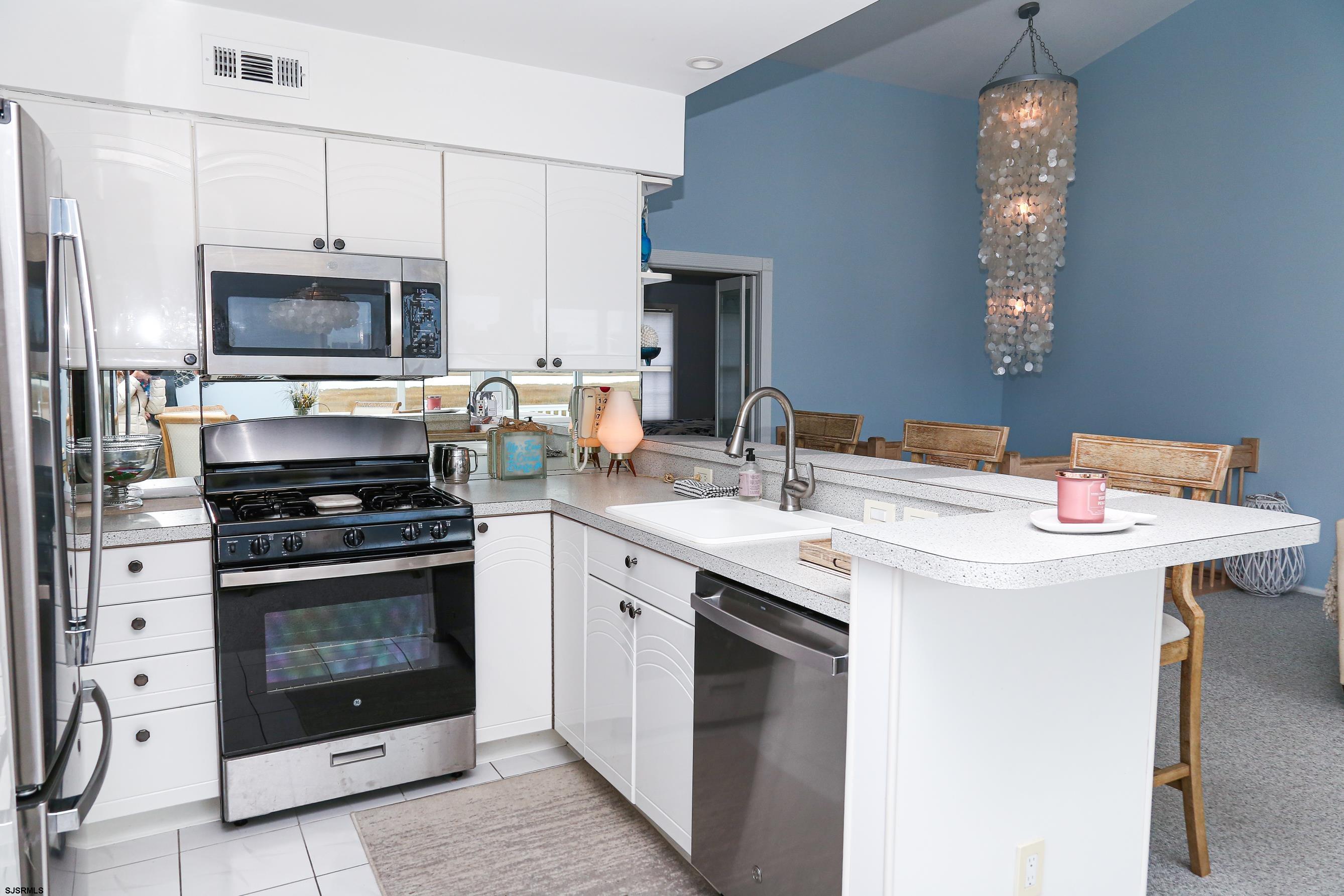 12 Gull Cove Brigantine, NJ 08203 - Photo 14 of 50 a kitchen with stainless steel appliances granite countertop a stove top oven a sink and a refrigerator