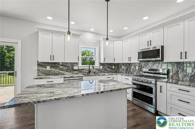 a kitchen with stainless steel appliances granite countertop a stove a sink and a microwave