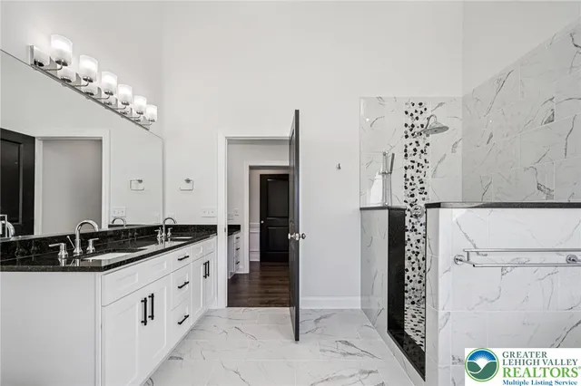 a spacious bathroom with a granite countertop double vanity and a mirror