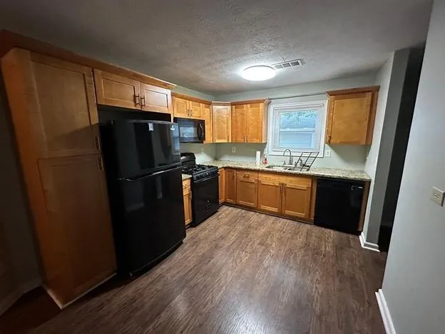 a kitchen with stainless steel appliances granite countertop a refrigerator a sink a stove a microwave and island with wooden floor