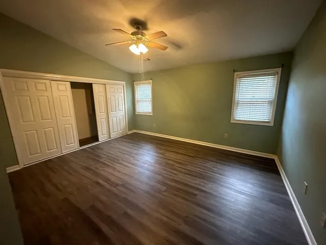 a view of an empty room with a window and wooden floor