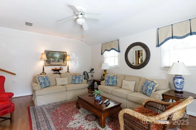 a living room with furniture a clock on wall and a window