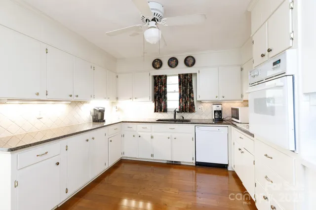 a kitchen with granite countertop white cabinets white appliances with a sink and dishwasher
