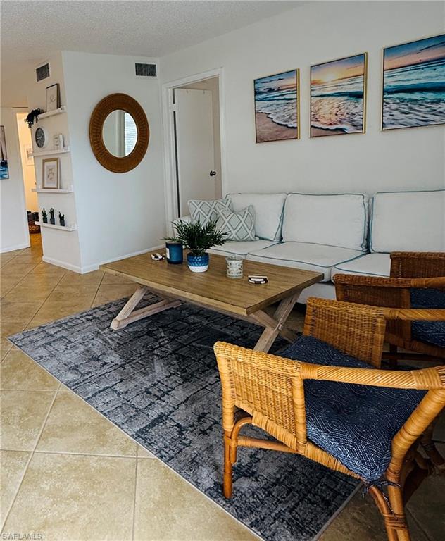 3250 10th Street North, Unit C8 Naples, FL 34103 - Photo 1 of 24 Spacious living area featuring tile flooring, built-in shelving, and a neutral color palette