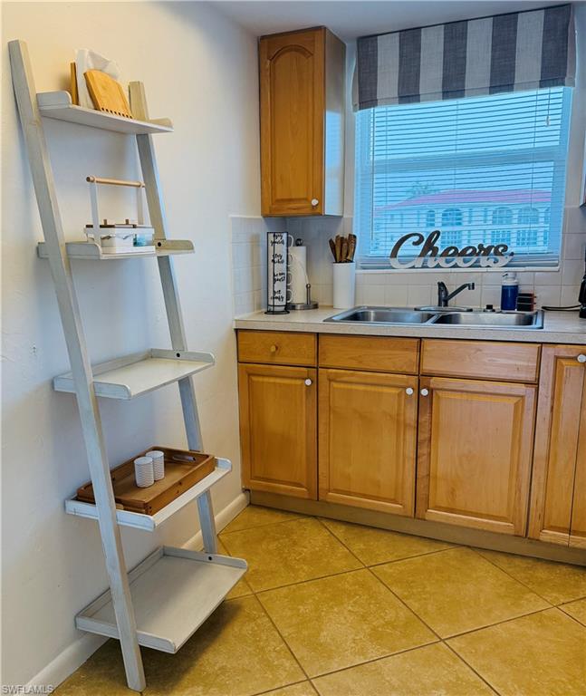 3250 10th Street North, Unit C8 Naples, FL 34103 - Photo 11 of 24 Kitchen featuring wood cabinetry, a double basin stainless steel sink, and light-toned countertops
