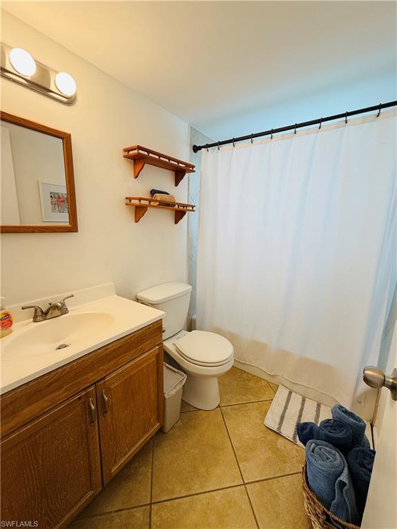 3250 10th Street North, Unit C8 Naples, FL 34103 - Photo 12 of 24 Bathroom featuring a wood-finish vanity with a built-in sink, a white shower curtain, and contrasting wall shelving